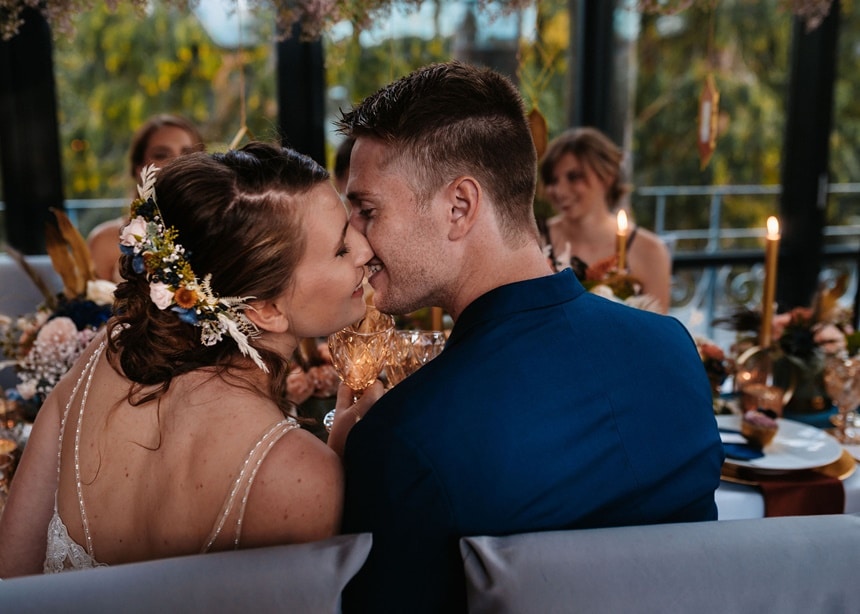 Autumn Colors küssendes Brautpaar am Tisch
