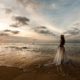 Flitterwochen Fotoshooting Braut im Brautkleid am Strand im Wasser